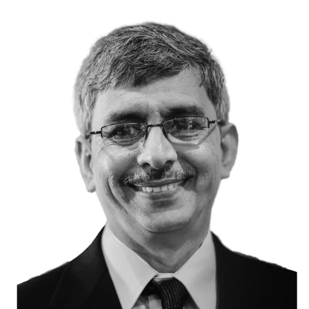 A person with long hair, wearing sunglasses, looks at the camera in a black and white image.